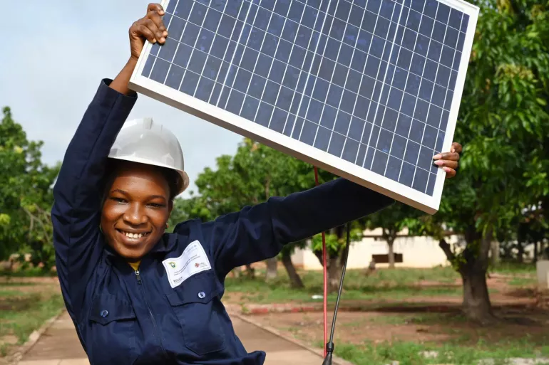 16 year-old-girl holds up solar panel.