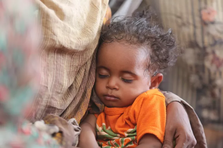 A child sleeps on his mother's lap in Atbara.