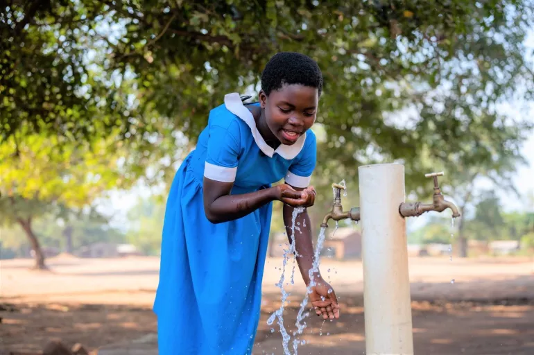 Noriah Kanyama drinking water at school from a tap installed with support from UNICEF.