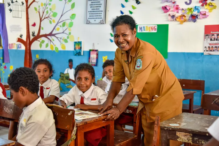 A school principal teaches second graders in a classroom in Indonesia.