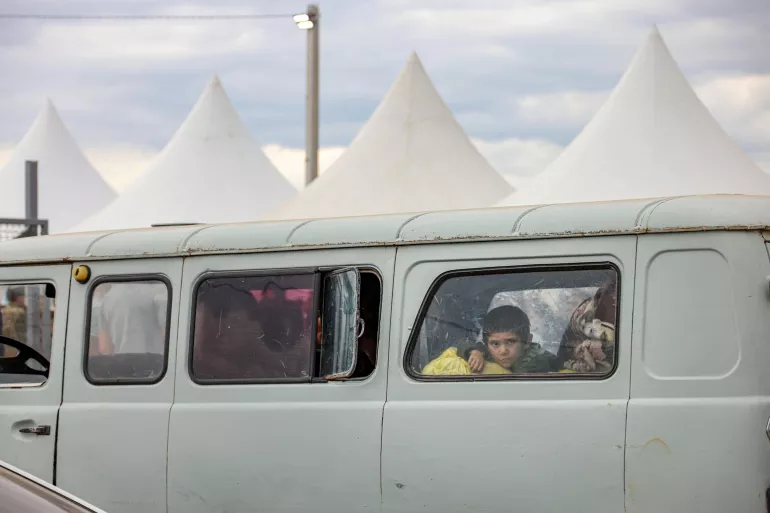 A child looks out through the window of a bus.