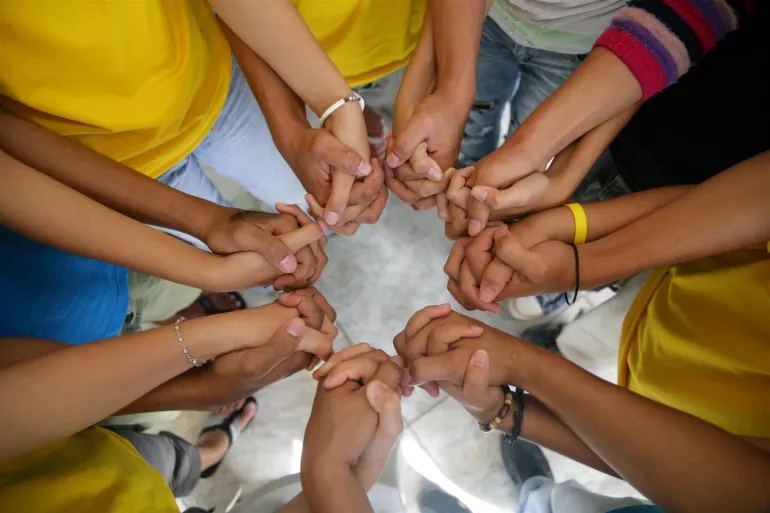 A group of children holding hands together in a circle