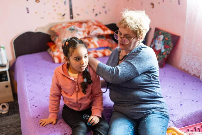 Community nurse uses a stethoscope to listen to five-year-old child's breathing.