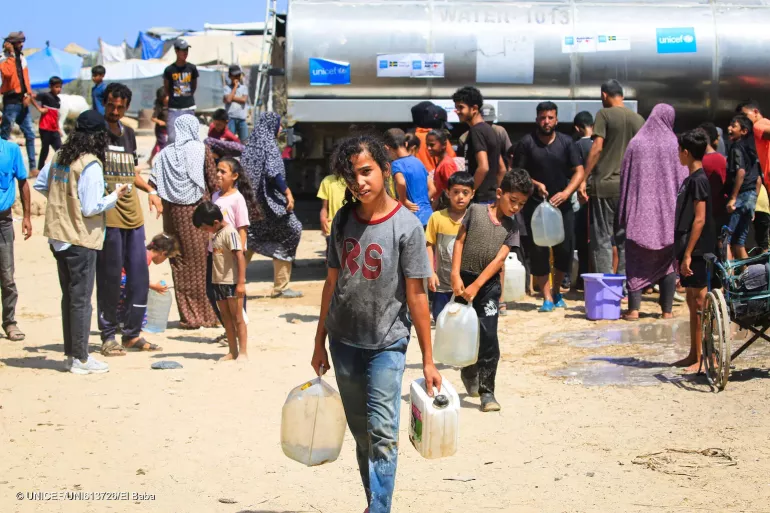 Gaza Strip. A girl holds two containers after filling them at a UNICEF-supported water tank in the Gaza Strip.