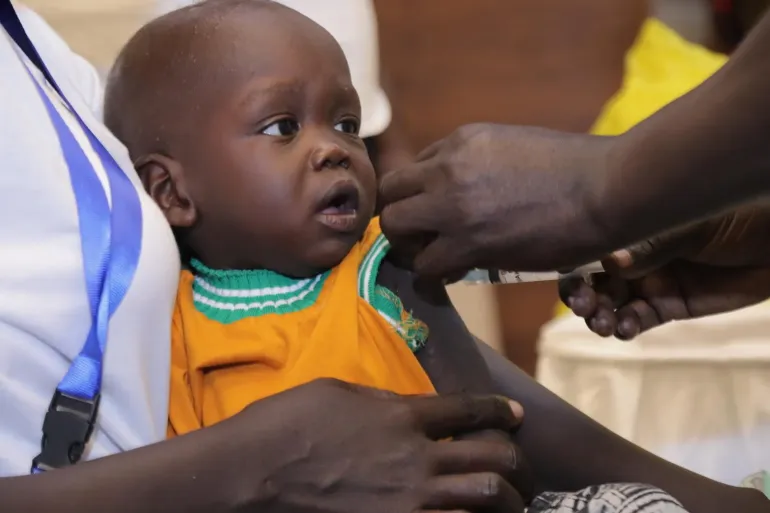 A child gets vaccinated against malaria by a health worker