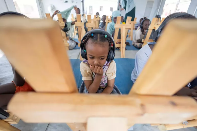 Sudan. A child listens on headphones during an e-learning programme for children who have been displaced.
