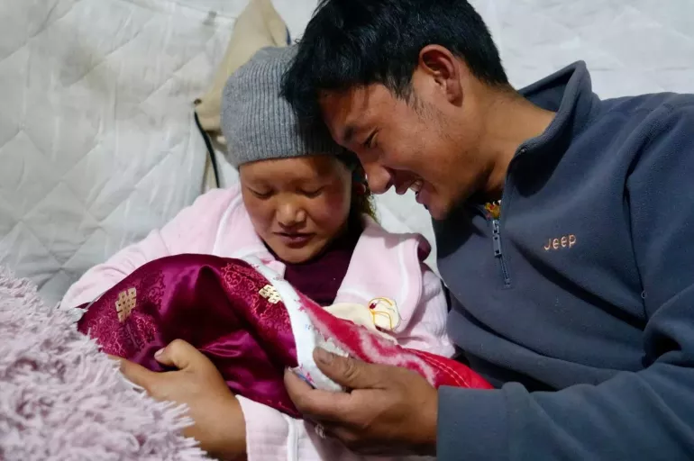 A mother and father hold their infant.