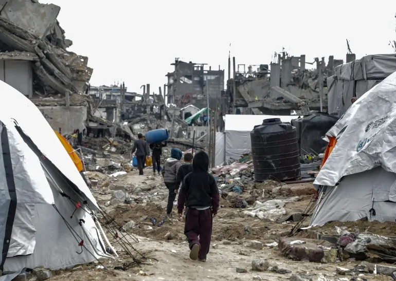Gaza Strip. Children walk past tents in Jabalia camp.