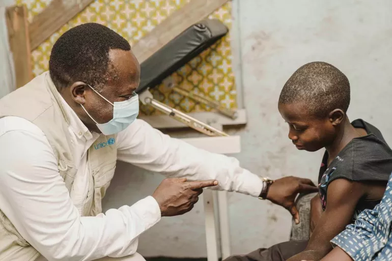 A man wearing a medical mask speaks to a young a boy.