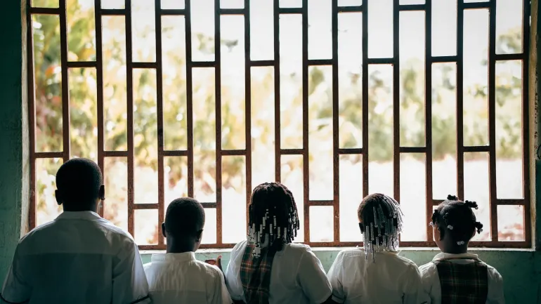 Un grupo de ni&ntilde;os y ni&ntilde;as ve a trav&eacute;s de una ventana en Colombia.