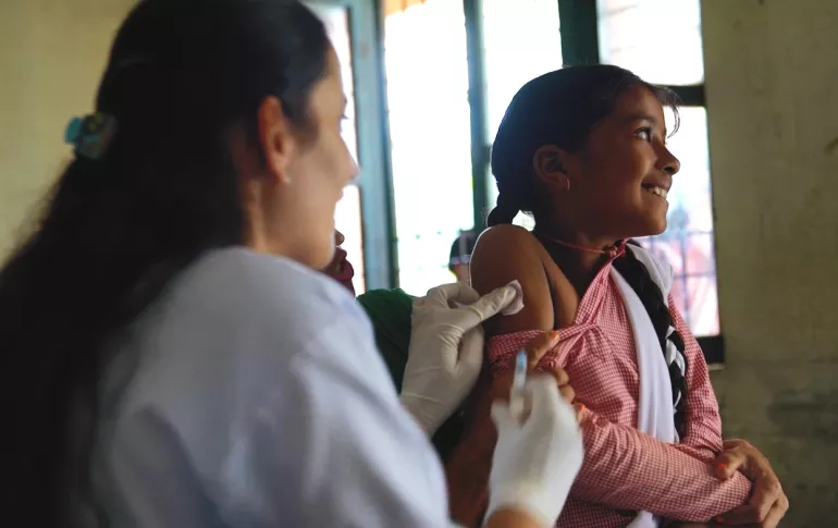 A child receives a vaccine via needle from a nurse.