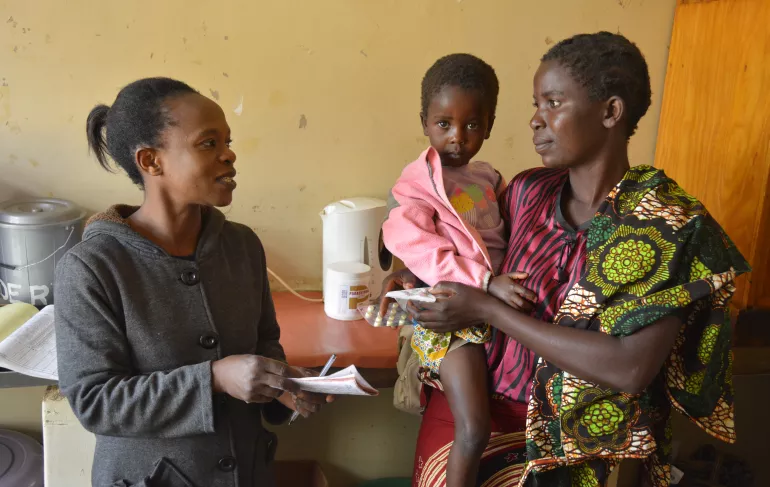 A woman sits with her child in a health clinic, Malawi