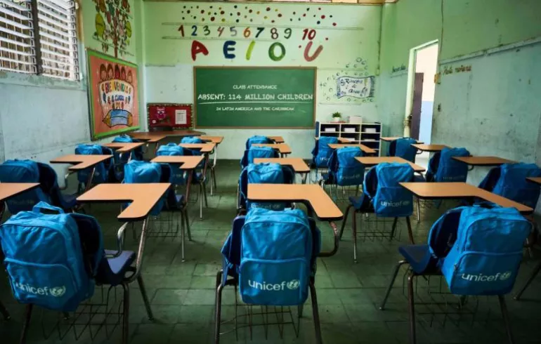 Empty classroom with UNICEF backpacks on chairs
