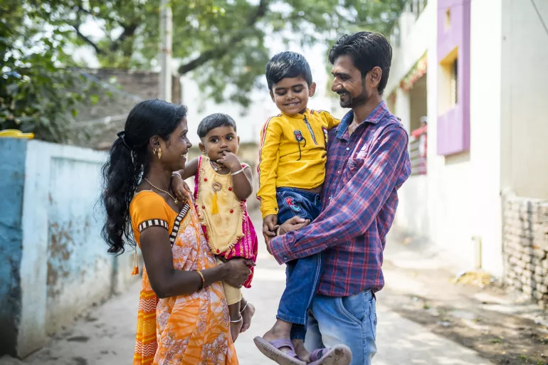 Smiling parents with their children outside their home.