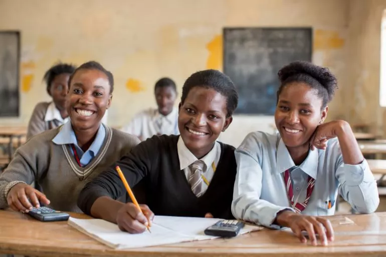 Tres ni&ntilde;as en una escuela de Zambia sonr&iacute;en