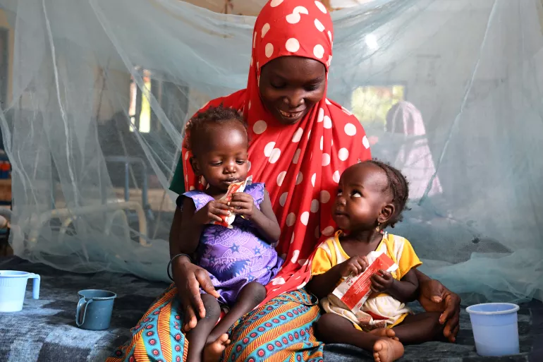 Nana Hadiza, 28, holds her twin daughters as they sit on a hospital bed at the CHU Hospital of Maradi, Niger. The twins are treated for malnutrition with Ready-to-Use Therapeutic Foods (RUTF).