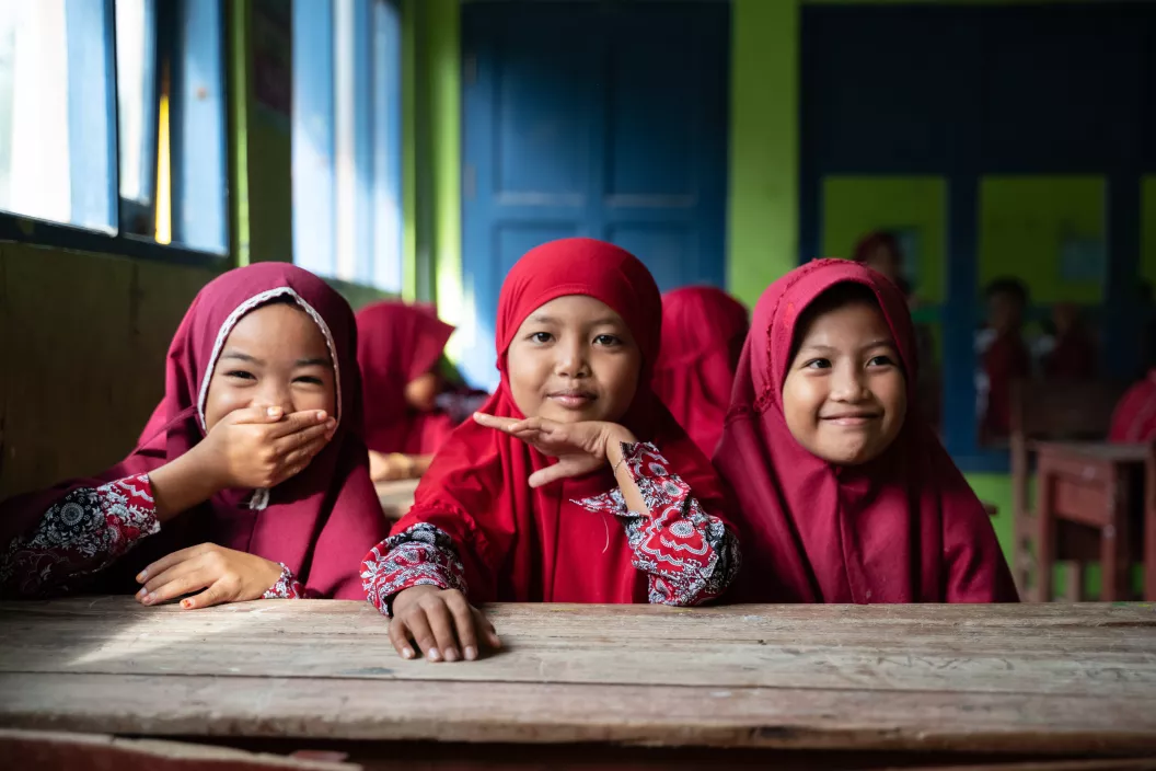 Des petites fille v&ecirc;tues de rouge sont assises dans une classe d'&eacute;cole