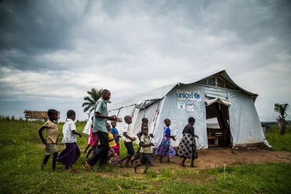 A teacher accompanies his students to their class in a temporary tent school in the Kasai region, Democratic Republic of the Congo, DRC.