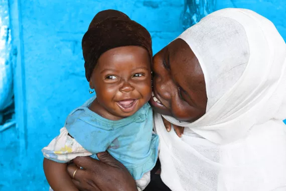 A mother holding her smiling baby next to her face