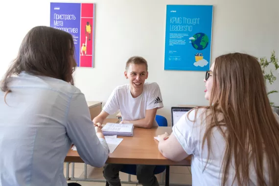 Three young adults siting at a desk having a discussion