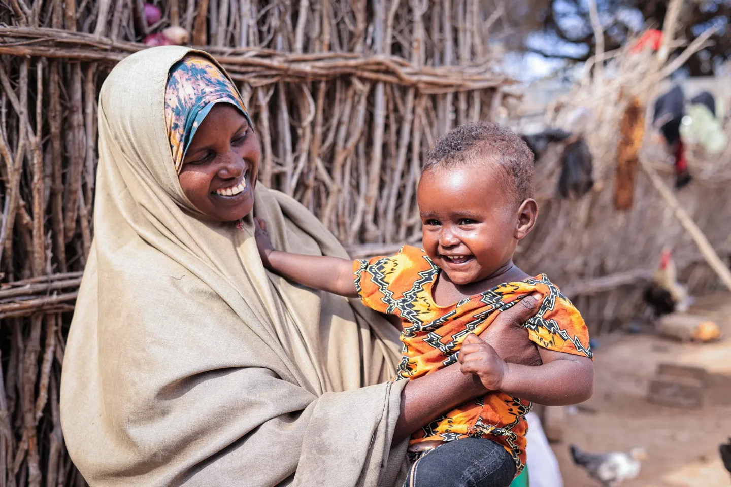 Jamaad holds her child and smiles at home in Jalalaqsi, Somalia.