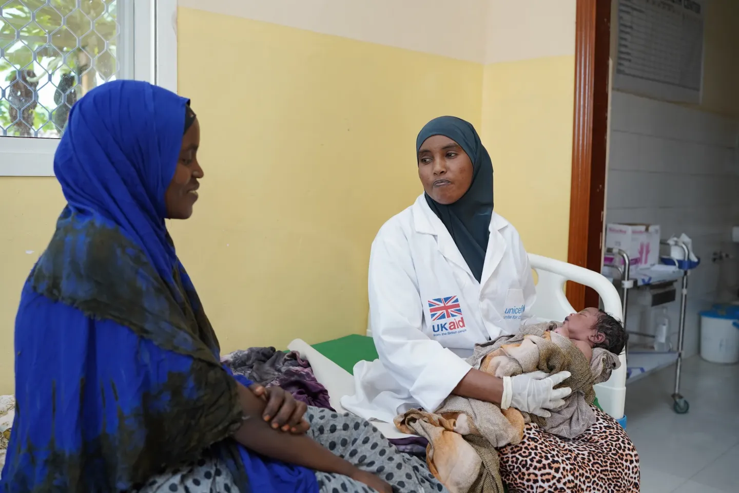 Huriyo Ahmed, a midwife at Eldheere Health Centre, holds a newborn she assisted during delivery while the mother looks on.