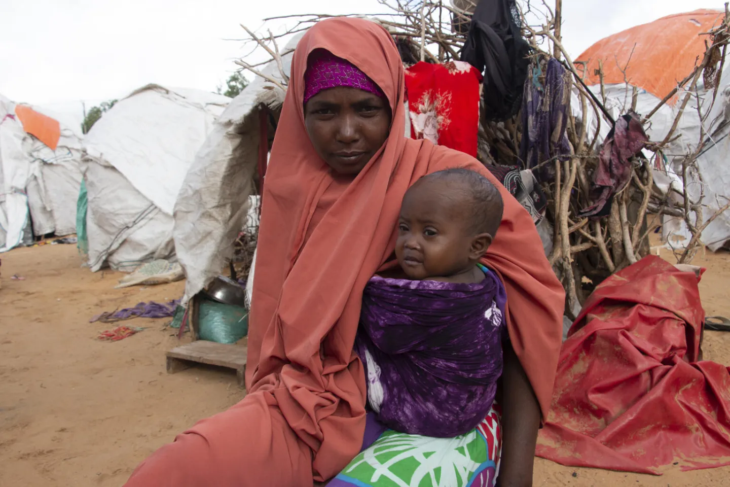 Khadijo sits with her daughter Sabirin, outside their makeshift house in the Gurman IDP camp.
