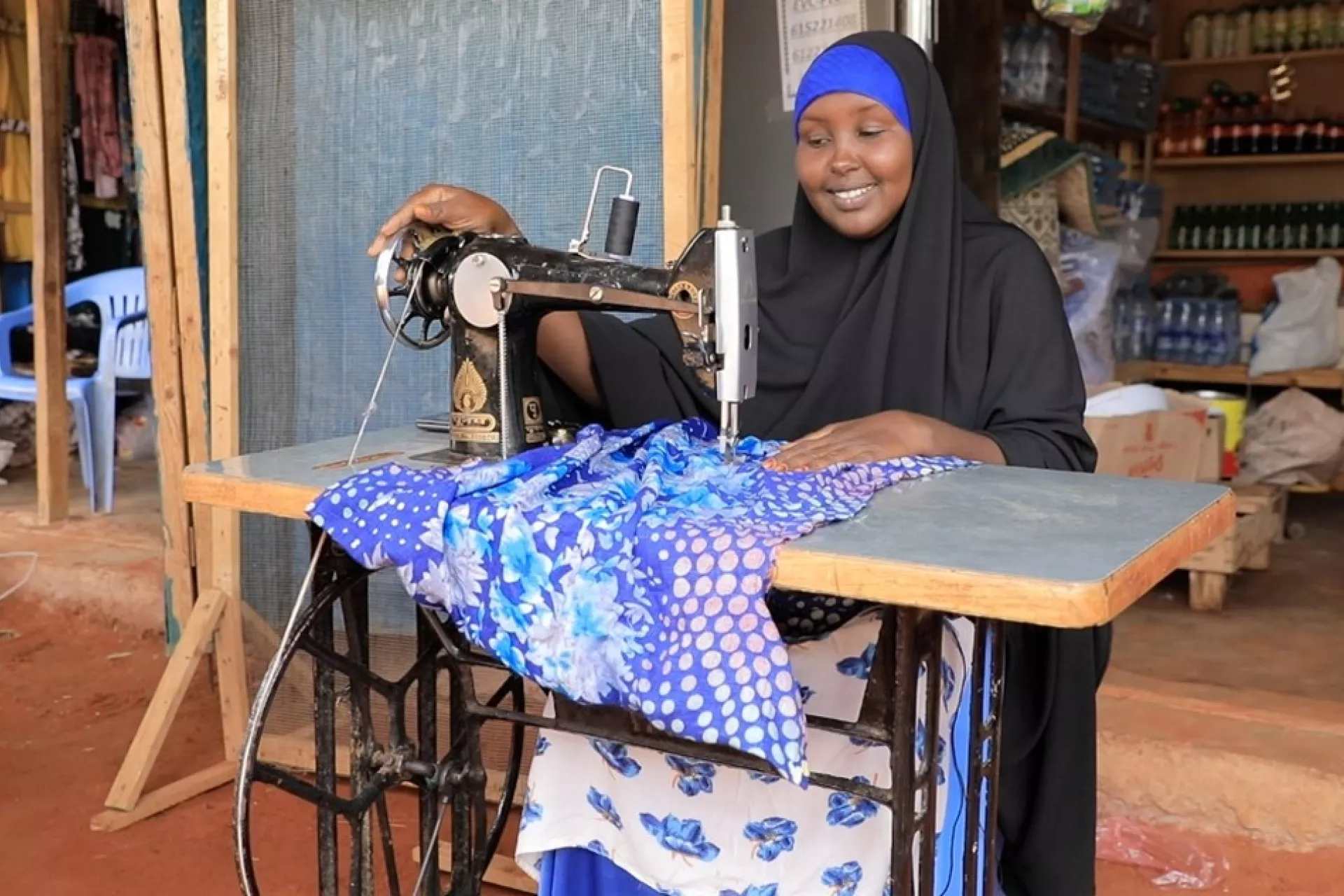 Faduma is sewing fabric at her shop.