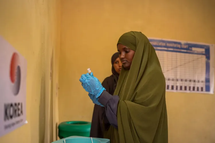 Amina prepares to vaccinate a child at Xalanley Health Centre, where she supports families to access essential immunization services.