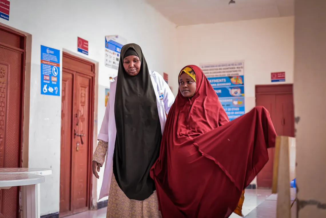 Kiin, supported by a nurse, walks through the maternity ward as she prepares to give birth at the health facility, where skilled care is helping ensure a safer delivery for mother and baby.
