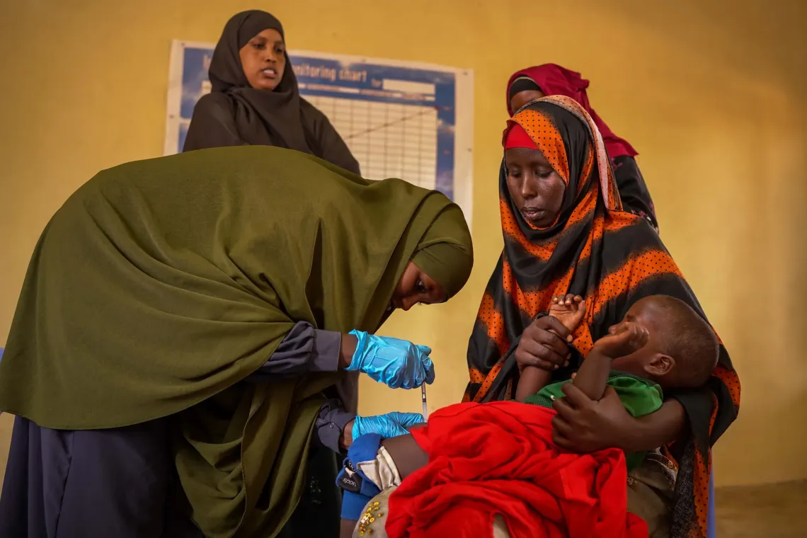 Maryan watches as her child receives a vaccination at Xalanley Health Centre, after receiving information that helped her make the decision to vaccinate her children.