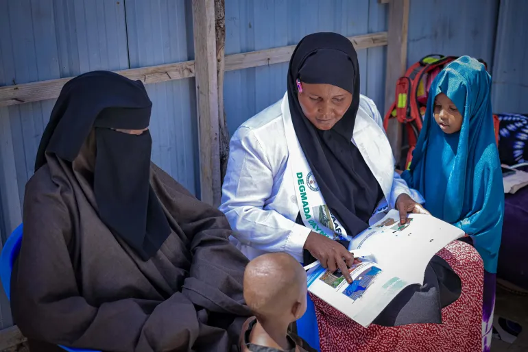 A community health worker engages with a mother, providing essential care and guidance to support the health and well-being of her child.