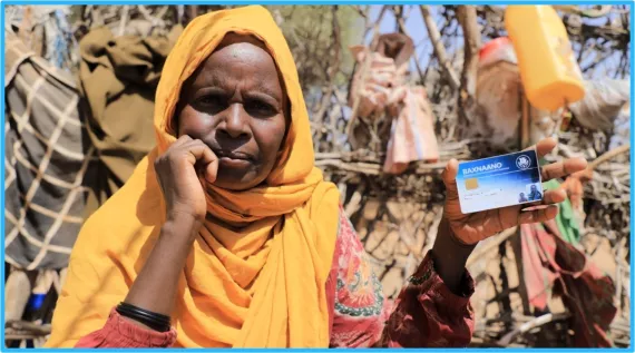Nuriye holds up her cash transfer card.