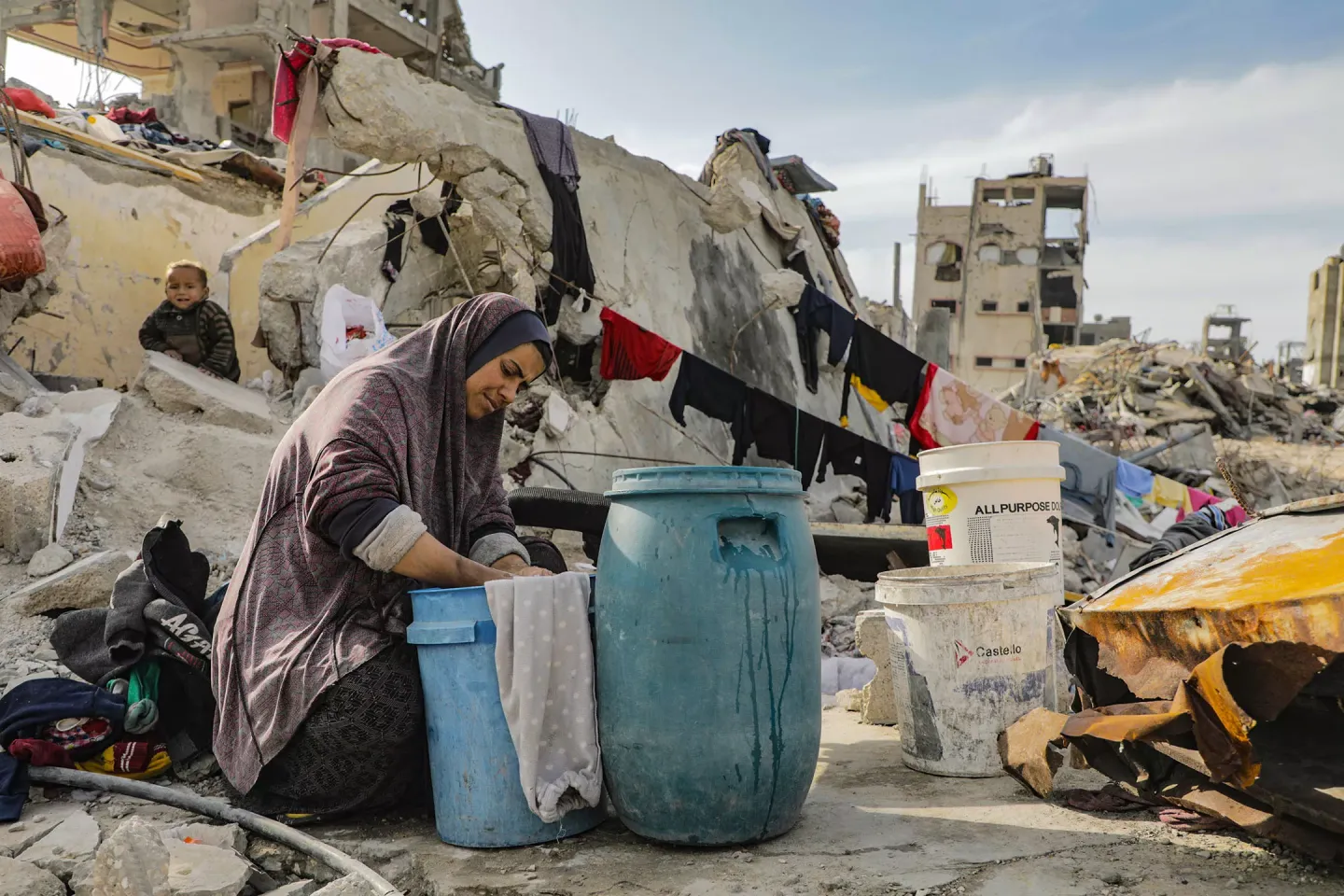 Toddler Adel al-Najma watches his mother wash clothes on the ruins of their home in Jabalya refugee camp. Potable water is very scarce in the camp, where tens of thousands of Palestinians have returned to live on or near their destroyed houses.