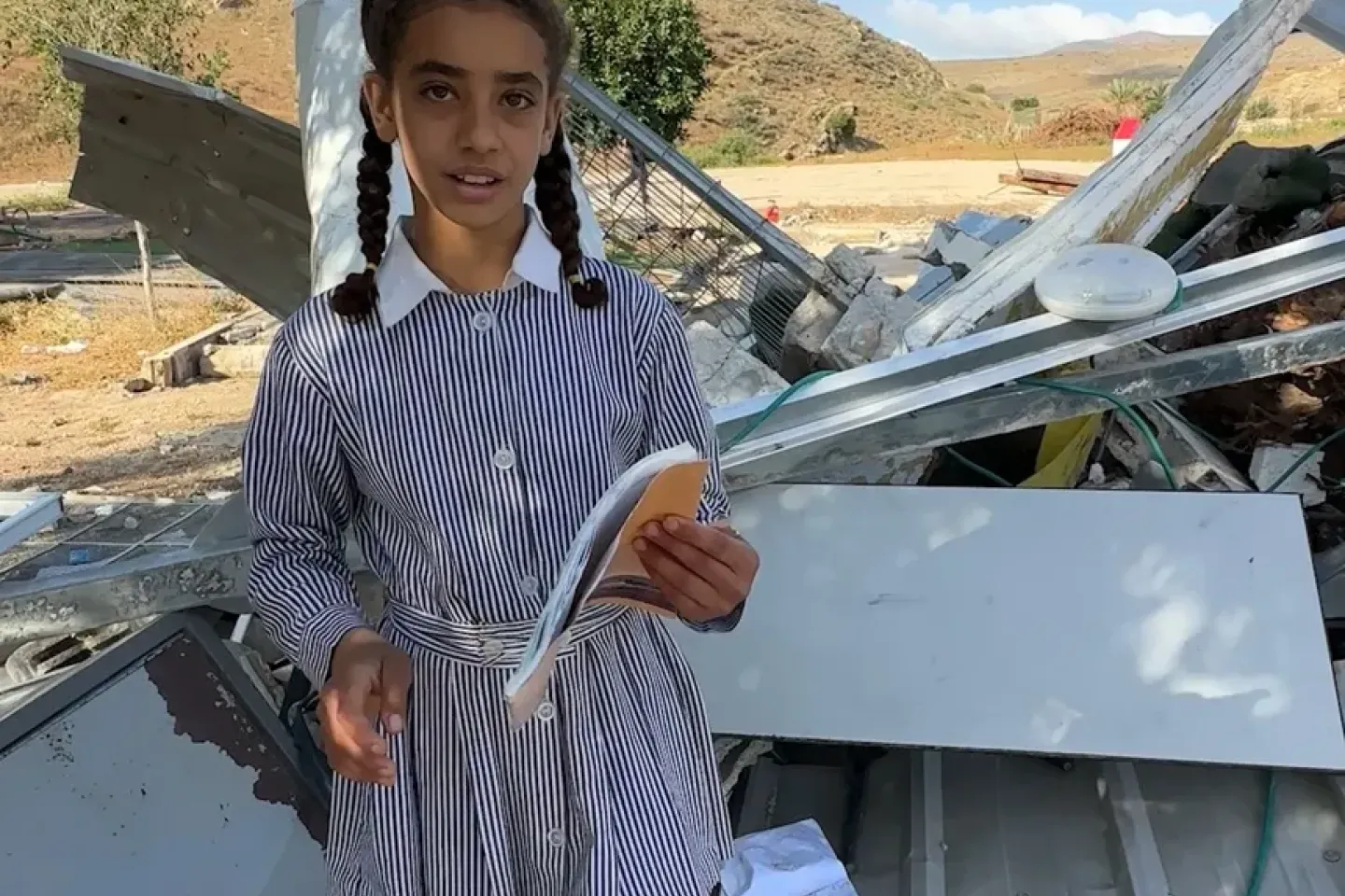 Girl standing in front of demolished school