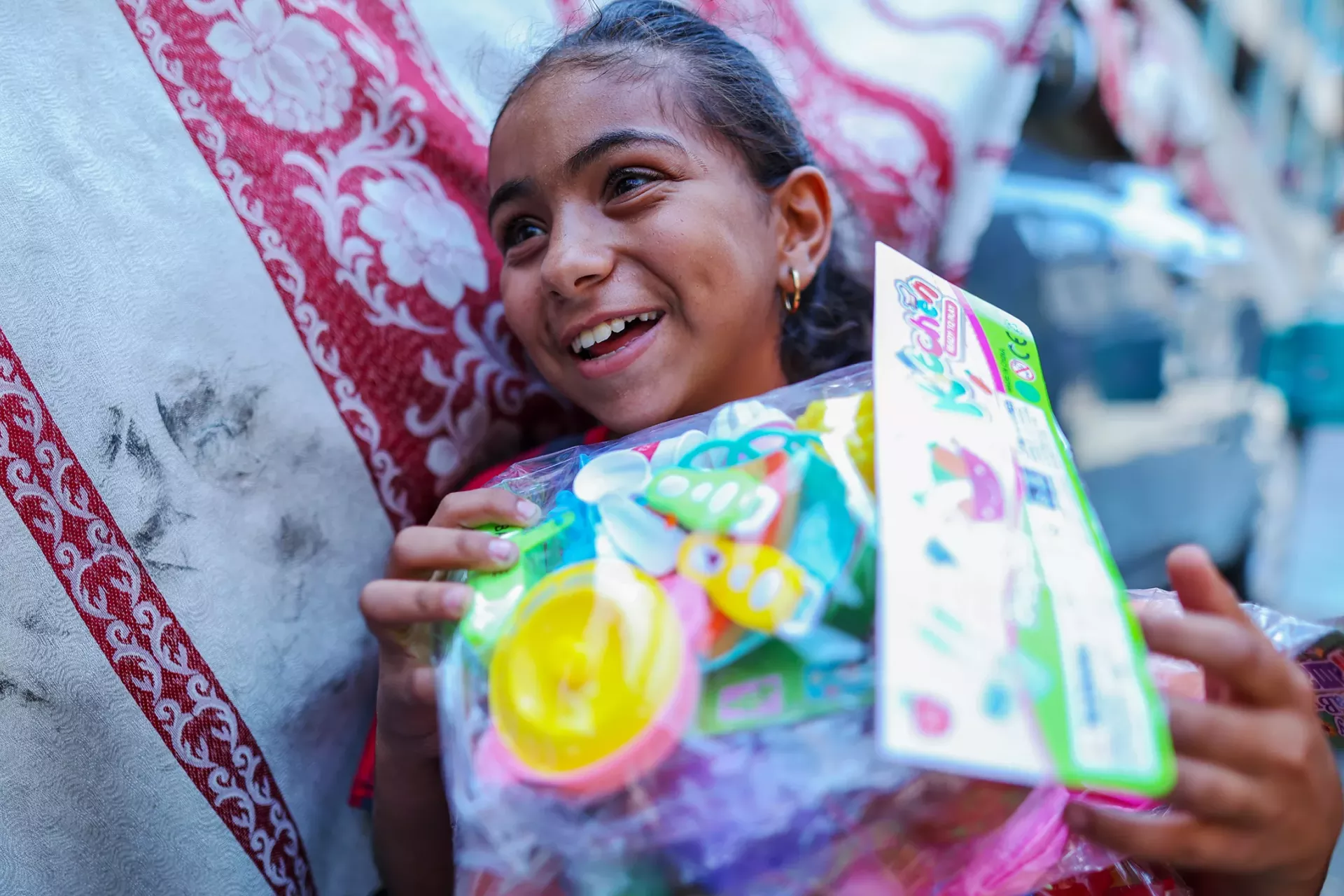 Ritaj, 12, smiles upon receiving a UNICEF psychosocial support kit, her own toys to play with in the displacement shelter where she lives in northern Gaza. 