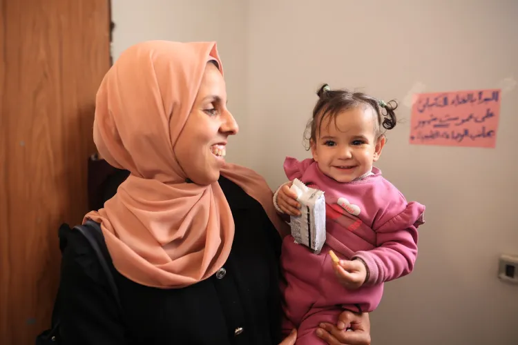 Saja Khas with her daughter receiving fortified food support during UNICEF&rsquo;s HEP distribution in Gaza.