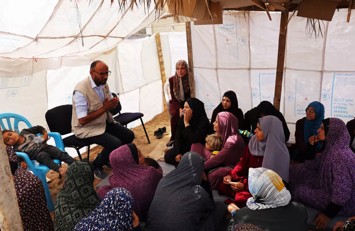 A UNICEF staff worker meets with mothers and female caregivers to raise awareness about the need for the identity bracelets and coping with trauma.