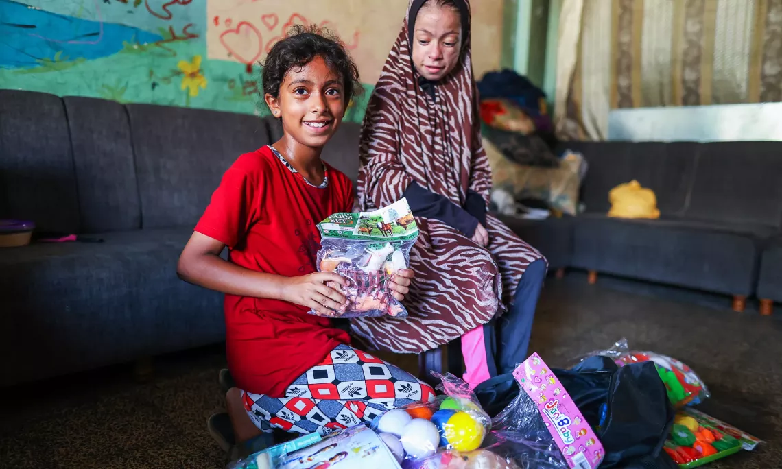 Batool (right) and a friend (left) look over the toys delivered by UNICEF to support their wellbeing and mental health. 