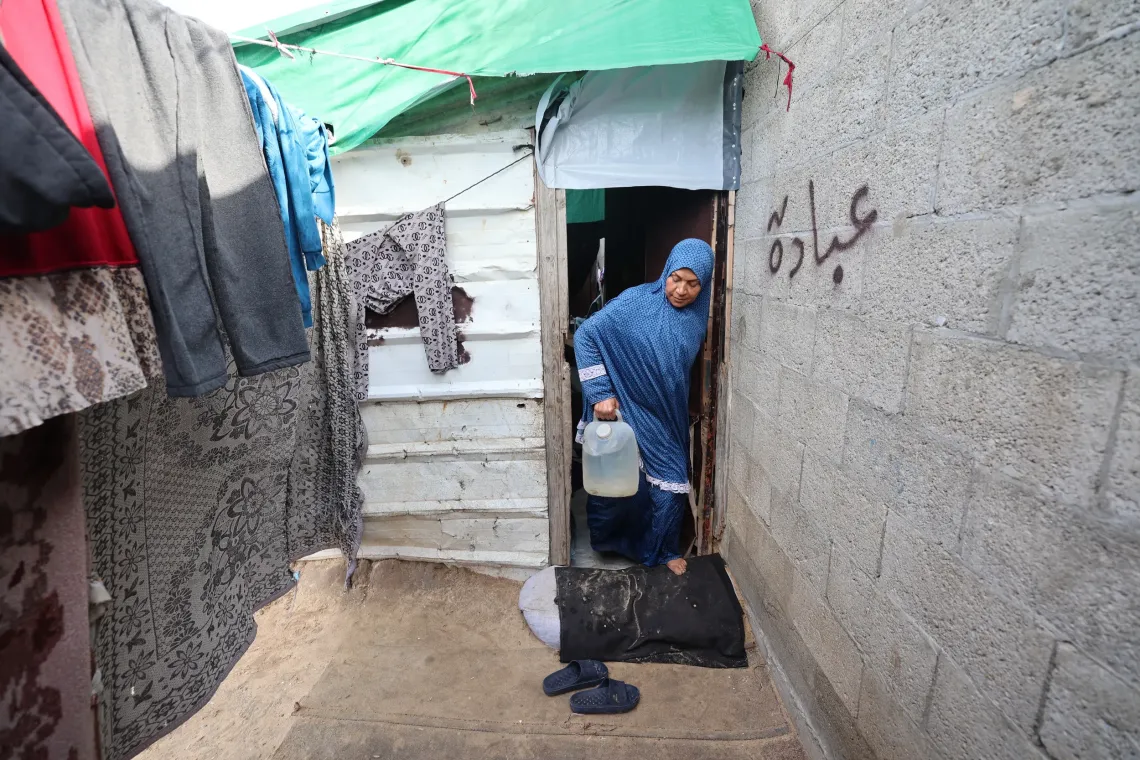 Latifa al-Farra, mother of eight, carries a UNICEF-issued water jug of clean water into her makeshift shelter in al-Zawayda, central Gaza.