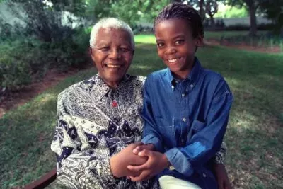 Nelson Mandela sits next to a young girl