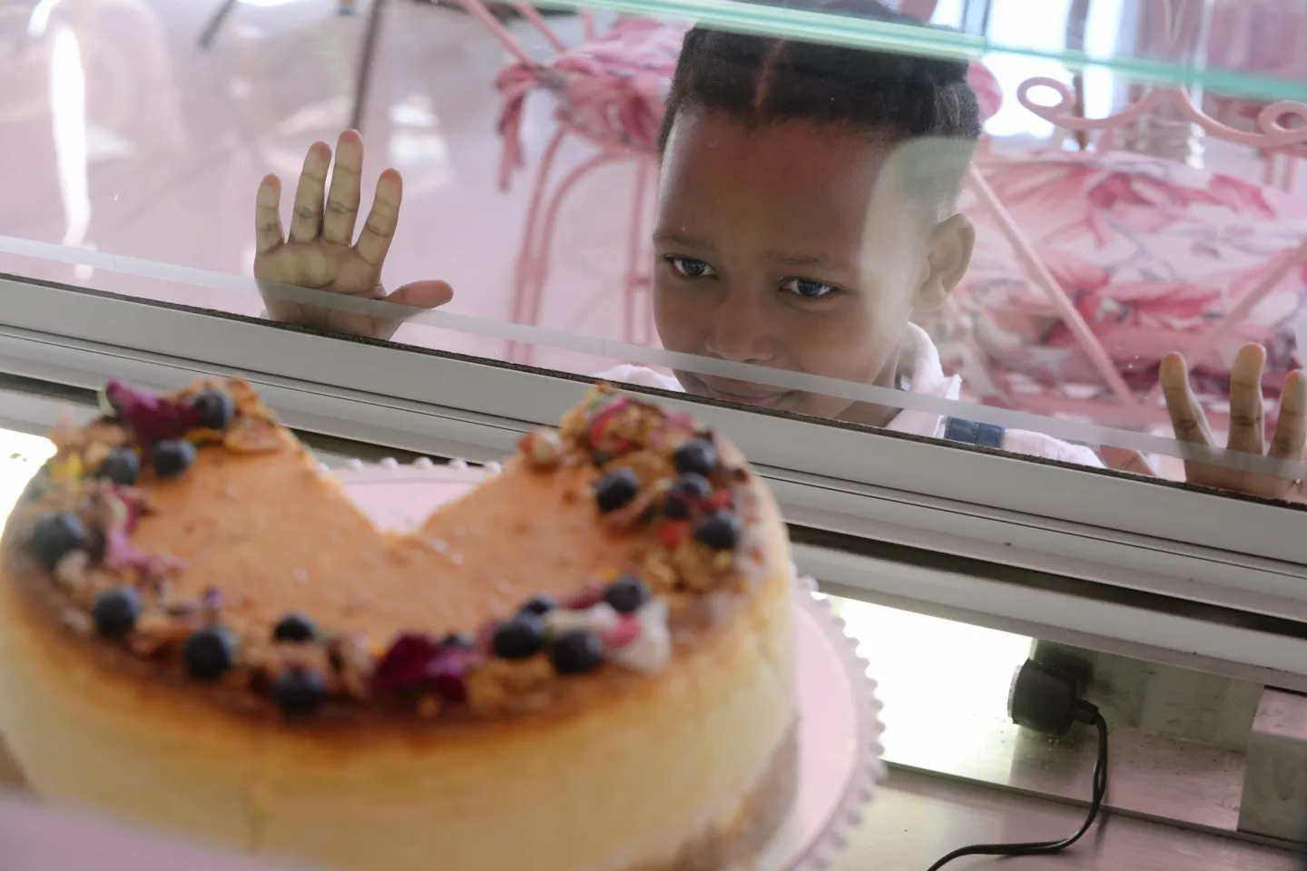 A girl looks a cake on display in a cafe.