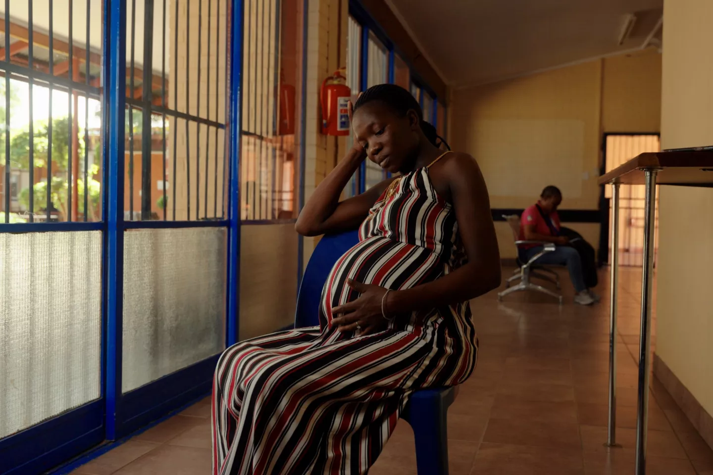 A pregnant woman sits on a chair resting