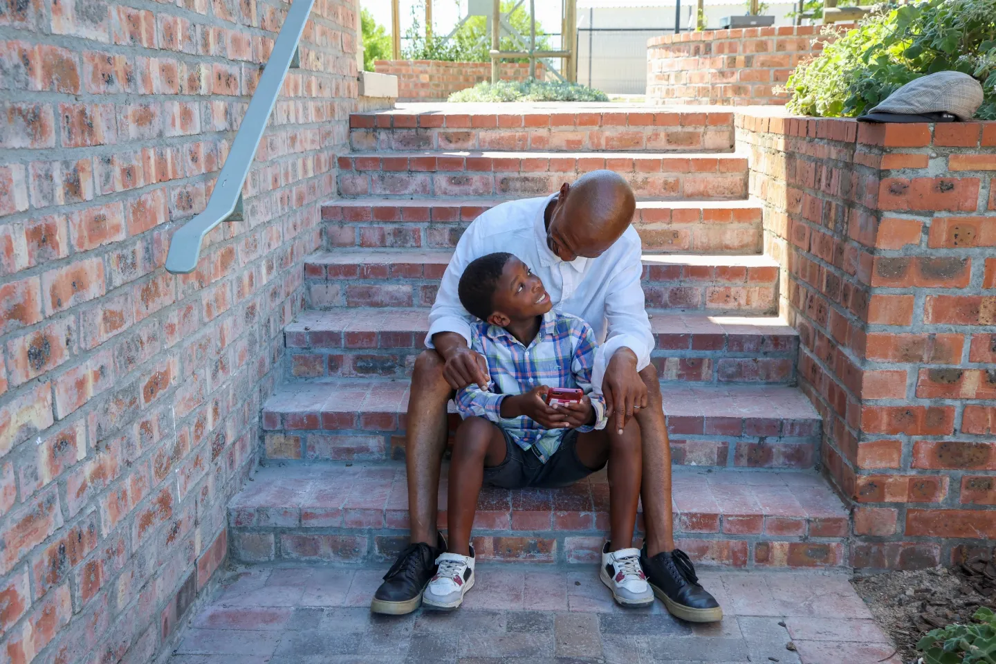 A father looks at a mobile phone with his son at Delft&nbsp;Nex Indawo-Yethu WCG eCentre in Cape Town, Western Cape province.