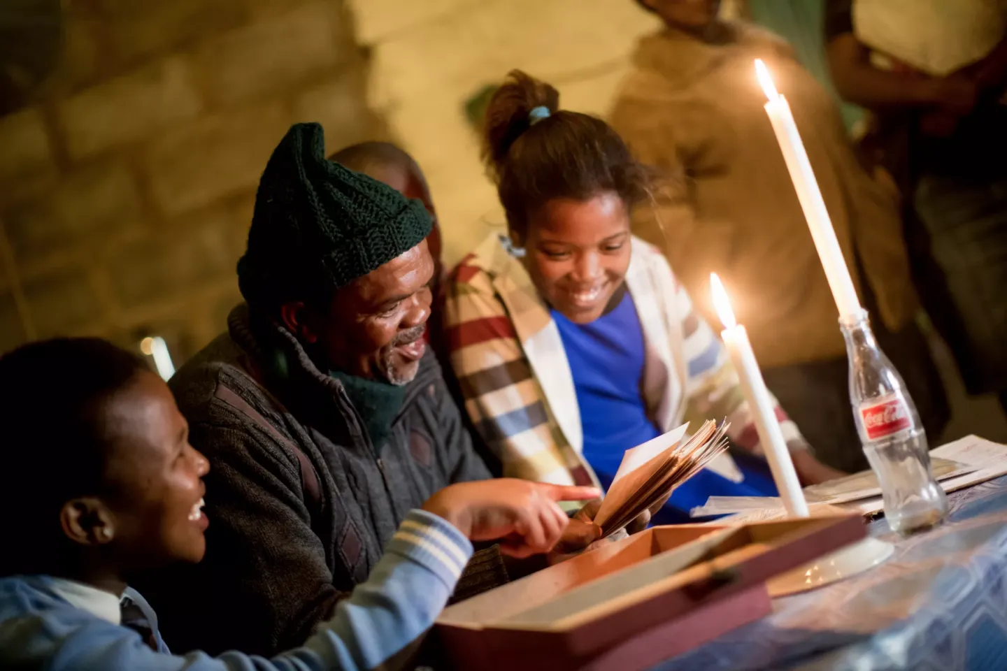 A man and two teenage children look at photos together.