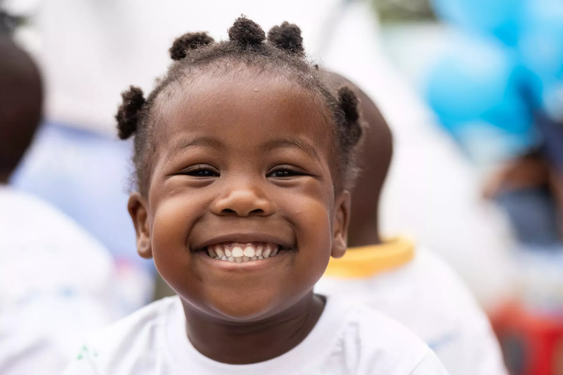 A little girl smiles brightly at the camera