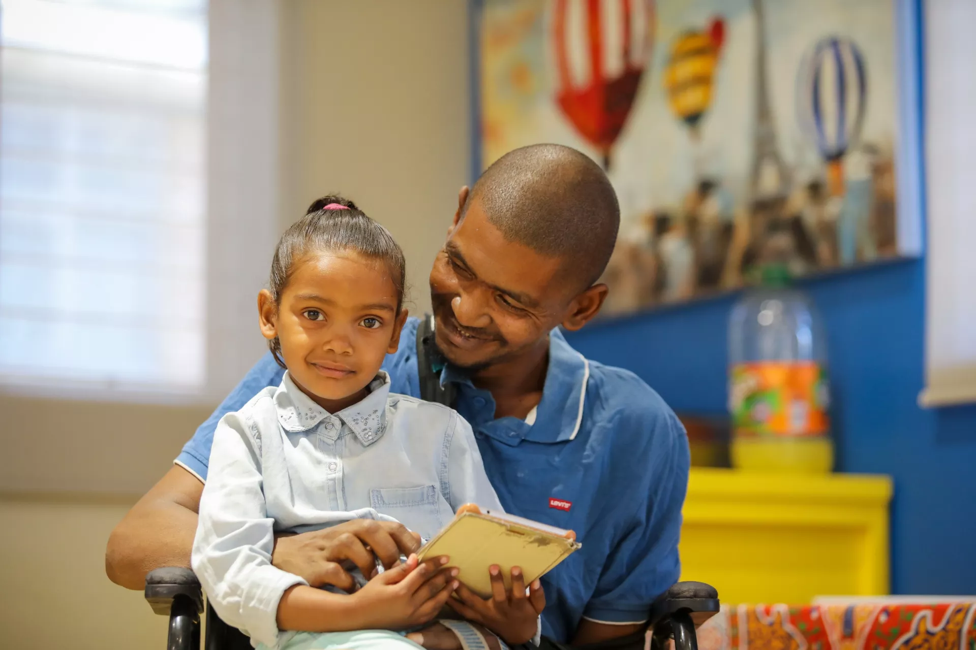 A father shares a moment with his daughter who is sitting on his lap.