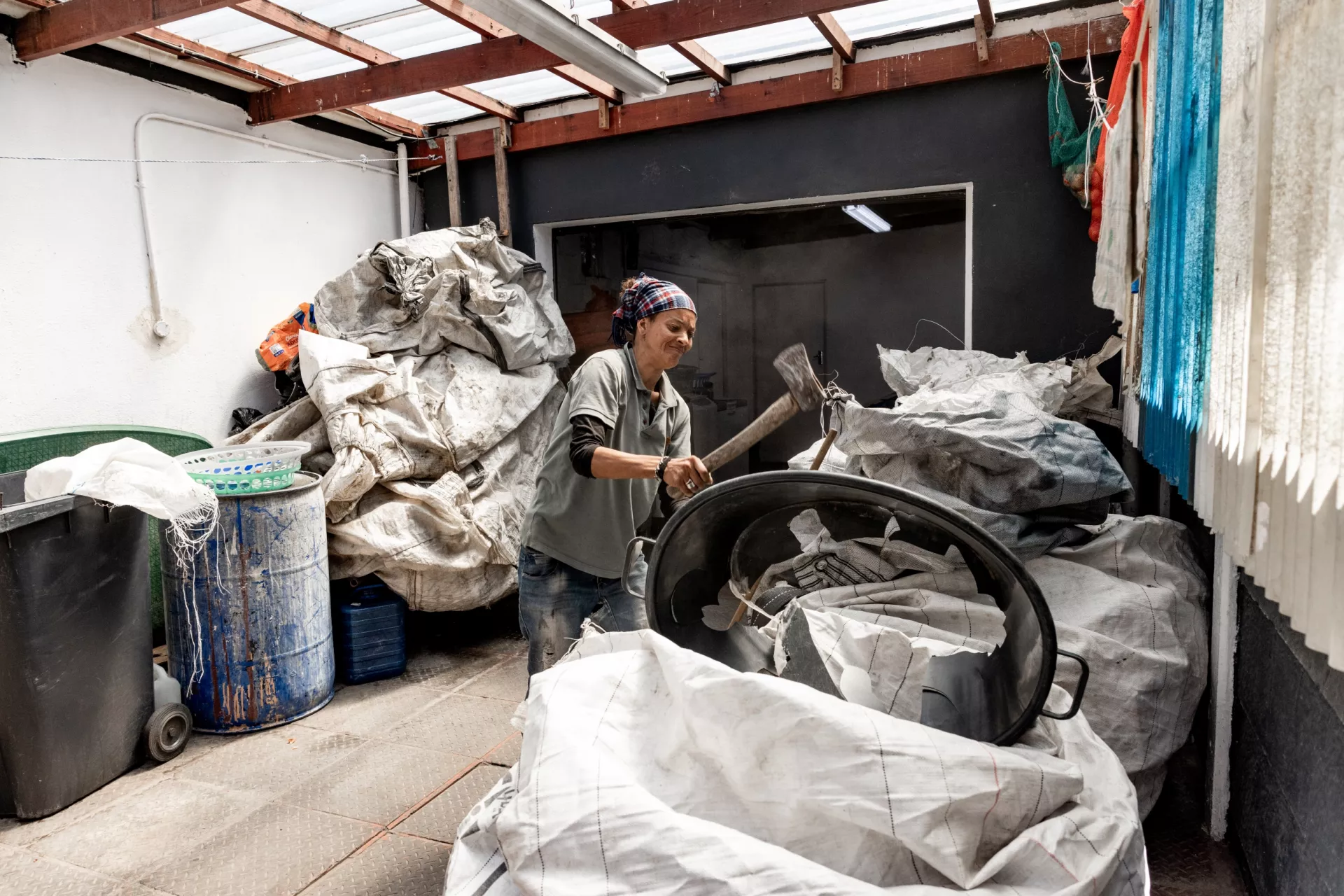 A woman hits a plastic tub to break it into smaller pieces.