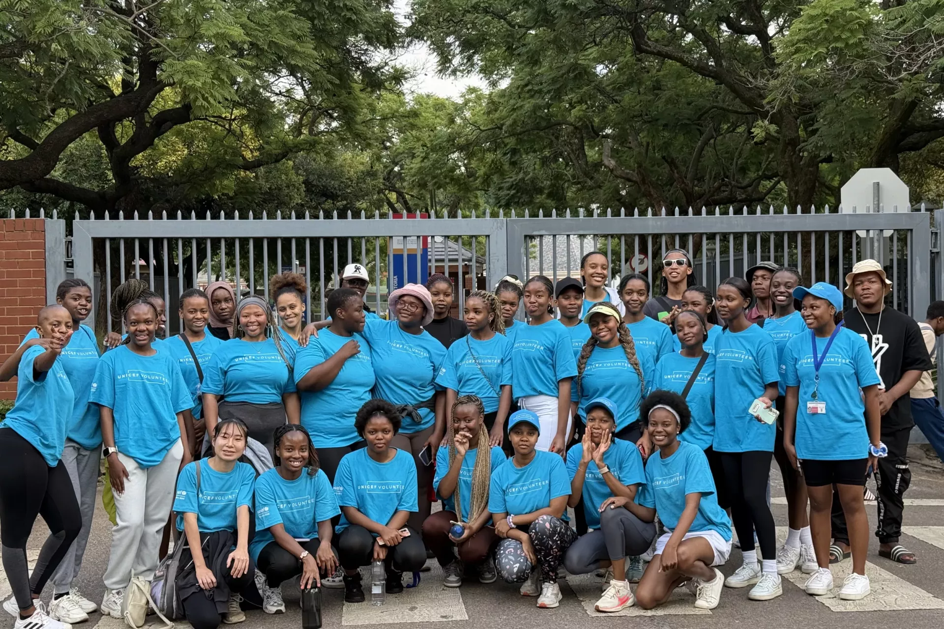 Student volunteers, wearing UNICEF Volunteer t-shirts, pose outside the gates of the University of Pretoria pose 