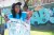 A young woman wearing a blue UNICEF Volunteer t-shirt carries a poster on child rights.